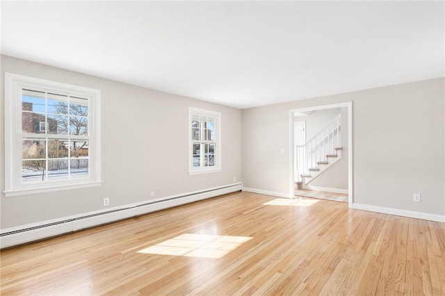 spare room featuring a baseboard radiator and light hardwood / wood-style floors