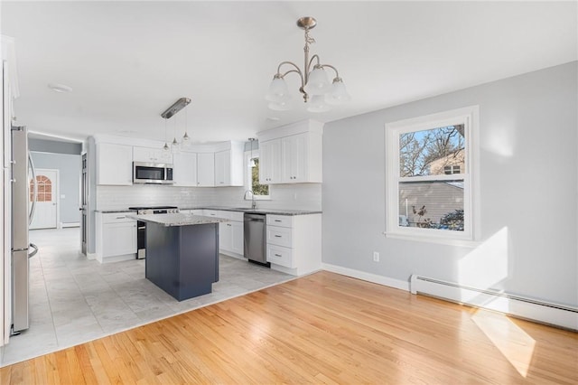 kitchen with a kitchen island, decorative light fixtures, a baseboard radiator, white cabinets, and stainless steel appliances