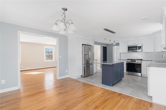 kitchen featuring pendant lighting, appliances with stainless steel finishes, a kitchen island, and a baseboard heating unit