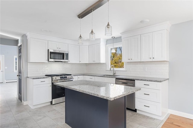 kitchen featuring sink, white cabinetry, hanging light fixtures, appliances with stainless steel finishes, and a kitchen island