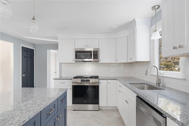 kitchen featuring blue cabinetry, stainless steel appliances, decorative light fixtures, and sink