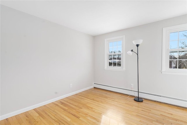 spare room with a baseboard heating unit and light hardwood / wood-style flooring