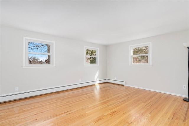 unfurnished room with a baseboard radiator, a wealth of natural light, and light hardwood / wood-style flooring