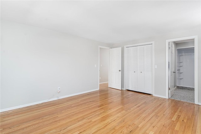 unfurnished bedroom with connected bathroom, a closet, and light wood-type flooring