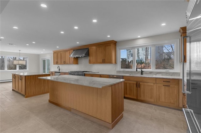 kitchen with wall chimney exhaust hood, sink, baseboard heating, high quality fridge, and a kitchen island