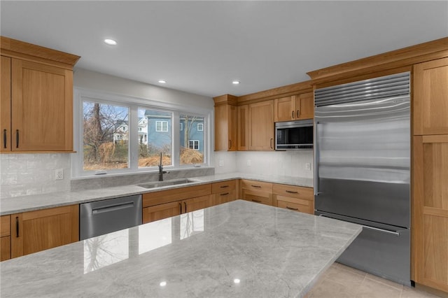 kitchen with light stone counters, sink, decorative backsplash, and appliances with stainless steel finishes