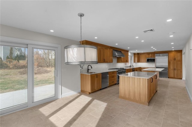 kitchen featuring pendant lighting, sink, high end appliances, a center island, and wall chimney range hood