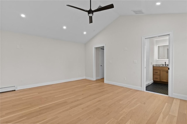 unfurnished bedroom featuring lofted ceiling, sink, ensuite bathroom, and light wood-type flooring