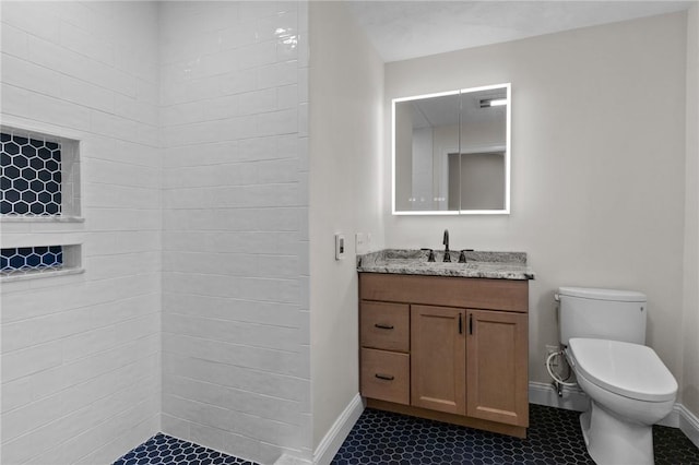 bathroom with vanity, tiled shower, and toilet