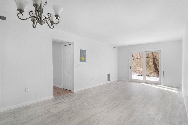 unfurnished living room featuring electric panel, a chandelier, and light wood-type flooring