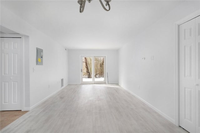 unfurnished room featuring electric panel and light hardwood / wood-style flooring