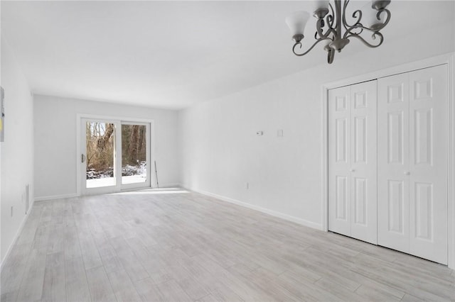 unfurnished living room featuring a notable chandelier and light wood-type flooring