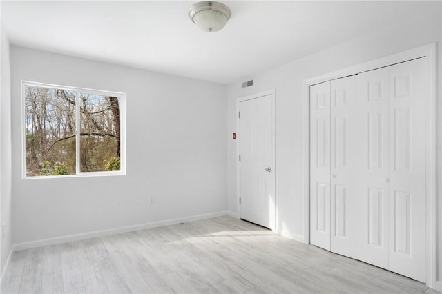 unfurnished bedroom with light wood-type flooring and a closet