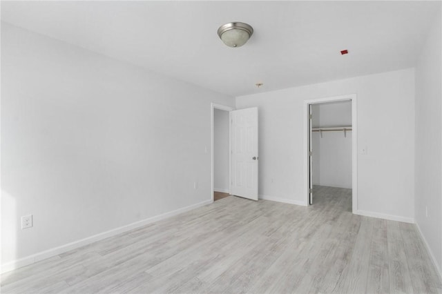 unfurnished bedroom featuring a walk in closet, light hardwood / wood-style floors, and a closet