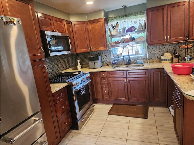 kitchen featuring tasteful backsplash, light stone countertops, appliances with stainless steel finishes, and sink