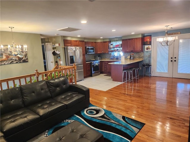 living room featuring sink, a notable chandelier, light hardwood / wood-style floors, and french doors