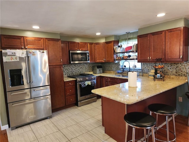 kitchen featuring a breakfast bar, sink, tasteful backsplash, appliances with stainless steel finishes, and kitchen peninsula