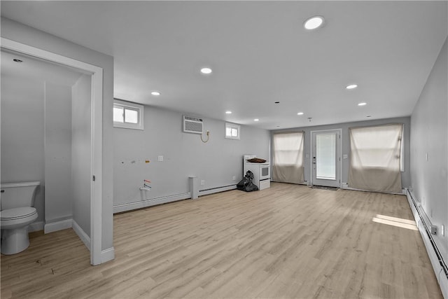 exercise area with a baseboard heating unit, a wall mounted air conditioner, and light hardwood / wood-style floors