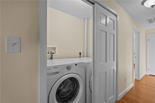 laundry area with washer and dryer and light wood-type flooring