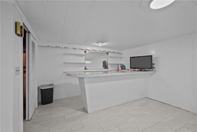 kitchen featuring light tile patterned floors, kitchen peninsula, and white cabinets