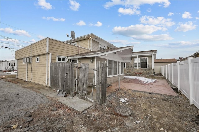 back of property featuring a wall unit AC and a patio area