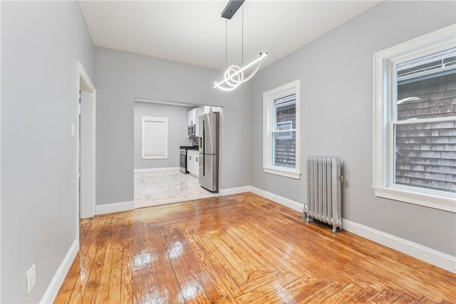 unfurnished dining area with radiator heating unit and light hardwood / wood-style floors