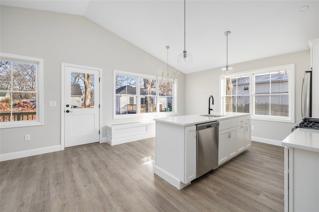 kitchen with sink, a center island with sink, appliances with stainless steel finishes, pendant lighting, and white cabinets