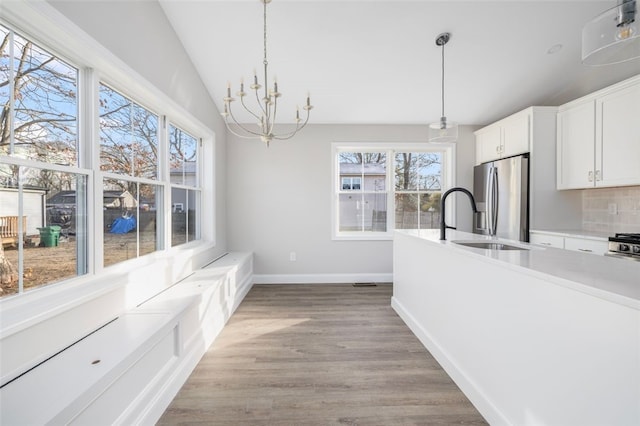 kitchen with hanging light fixtures, stainless steel refrigerator with ice dispenser, white cabinets, and light hardwood / wood-style floors