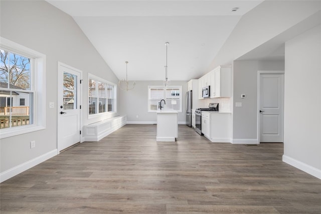 unfurnished living room featuring plenty of natural light, sink, and dark wood-type flooring