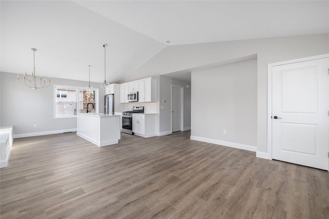 unfurnished living room with vaulted ceiling, an inviting chandelier, sink, and hardwood / wood-style floors