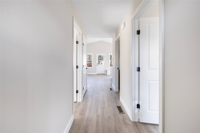 hallway with lofted ceiling and light hardwood / wood-style flooring