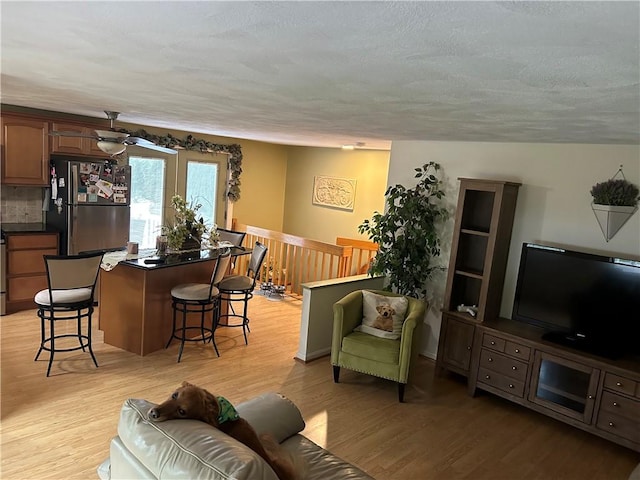 living room with ceiling fan, light hardwood / wood-style floors, and a textured ceiling