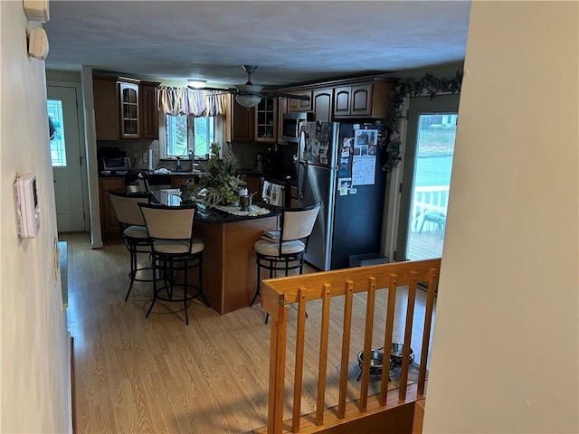 kitchen featuring a kitchen breakfast bar, tasteful backsplash, light wood-type flooring, and refrigerator