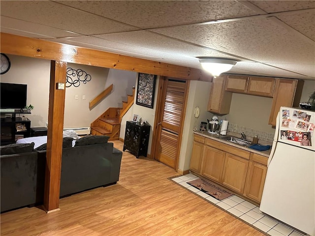 kitchen featuring white refrigerator, sink, a drop ceiling, and light hardwood / wood-style floors