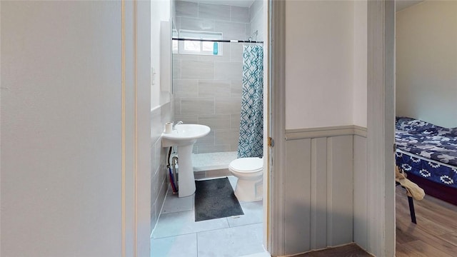 bathroom featuring tile patterned floors, toilet, sink, and a tile shower