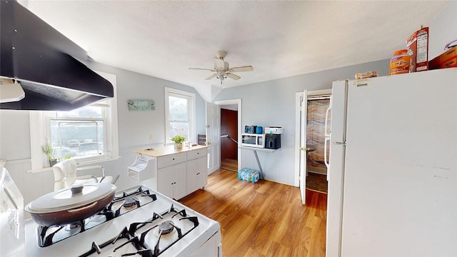 kitchen with white appliances, ventilation hood, light hardwood / wood-style flooring, ceiling fan, and white cabinets