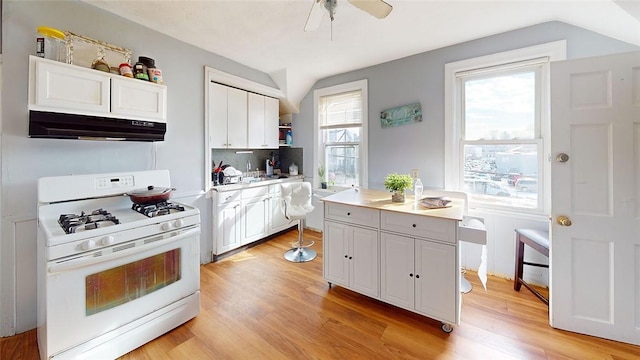 kitchen with gas range gas stove, white cabinetry, tasteful backsplash, light hardwood / wood-style flooring, and a kitchen island