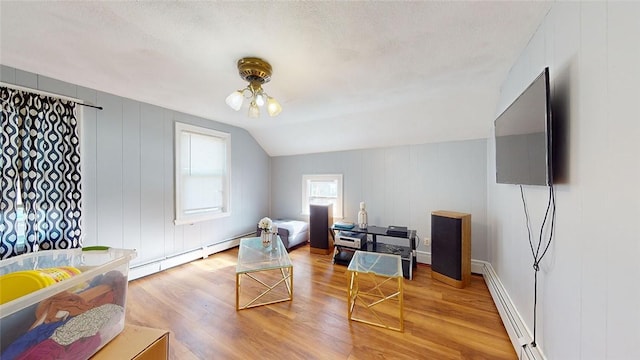 bedroom with hardwood / wood-style floors, a baseboard radiator, a textured ceiling, and vaulted ceiling