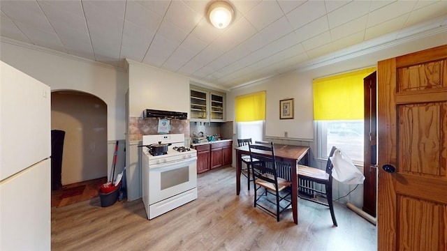 kitchen with crown molding, white appliances, light hardwood / wood-style flooring, range hood, and tasteful backsplash