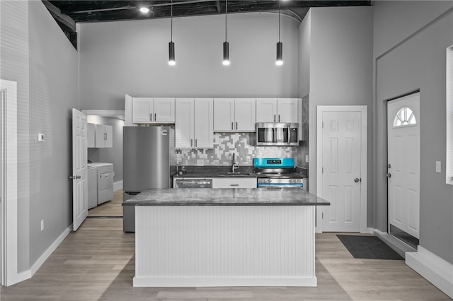 kitchen with sink, white cabinetry, separate washer and dryer, appliances with stainless steel finishes, and a high ceiling