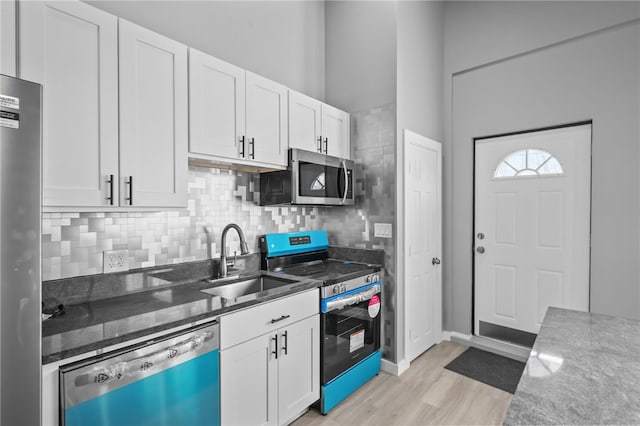 kitchen with stainless steel appliances, stone countertops, sink, and white cabinets