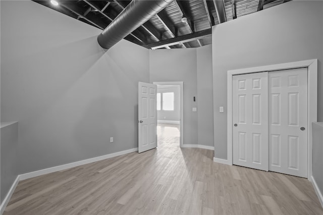 interior space featuring a towering ceiling and light wood-type flooring