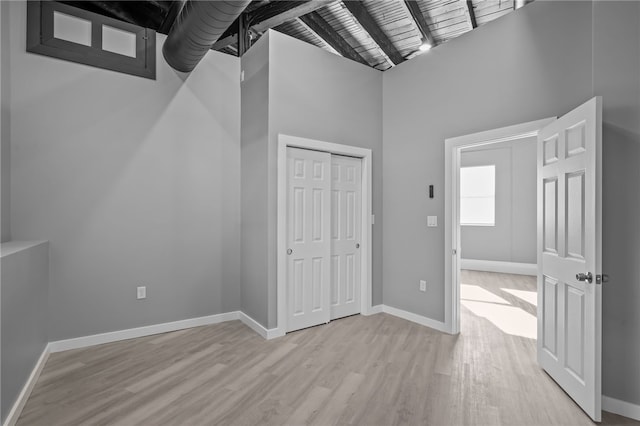 interior space featuring beam ceiling, a towering ceiling, and light wood-type flooring