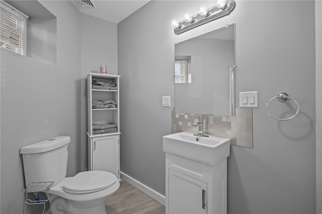 bathroom featuring vanity, backsplash, wood-type flooring, and toilet