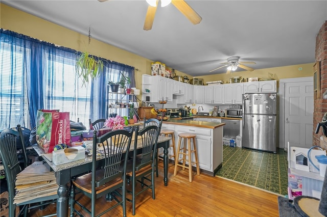 kitchen with appliances with stainless steel finishes, sink, white cabinets, kitchen peninsula, and light wood-type flooring