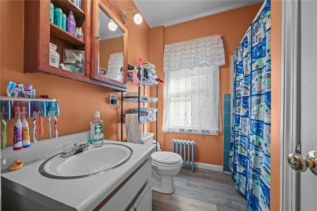 bathroom featuring hardwood / wood-style floors, vanity, radiator heating unit, and toilet