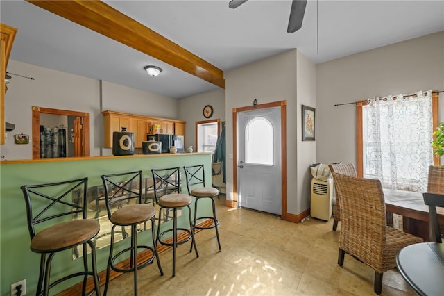 dining area featuring ceiling fan and beamed ceiling