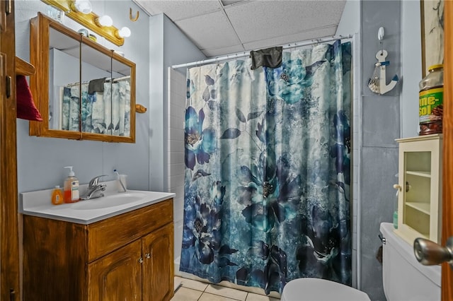 bathroom with a paneled ceiling, tile patterned flooring, vanity, a shower with curtain, and toilet