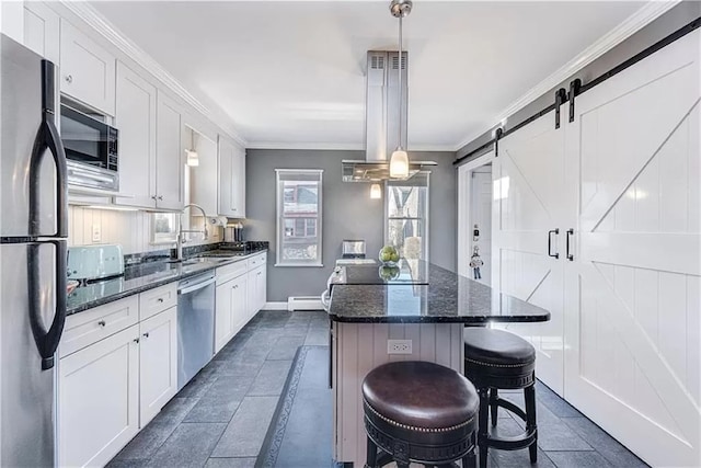 kitchen featuring appliances with stainless steel finishes, white cabinetry, sink, dark stone countertops, and hanging light fixtures