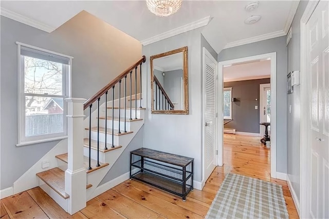 staircase featuring hardwood / wood-style flooring, ornamental molding, a healthy amount of sunlight, and baseboard heating